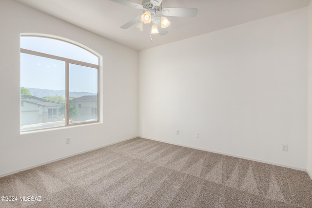 carpeted empty room featuring ceiling fan and a mountain view