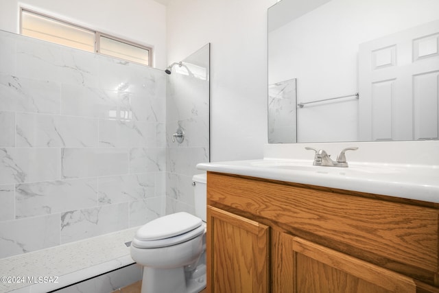 bathroom with vanity, toilet, and tiled shower