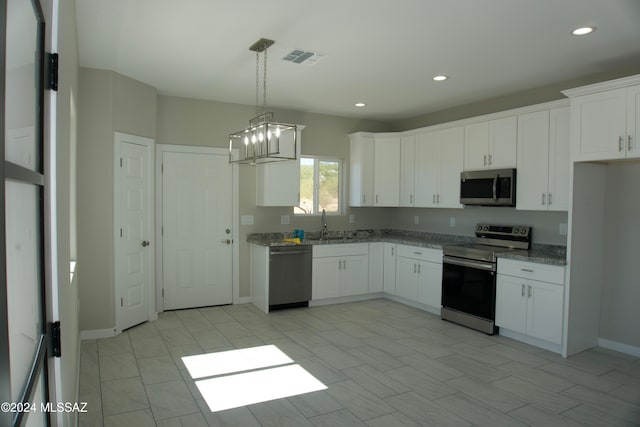 kitchen with sink, appliances with stainless steel finishes, light stone countertops, hanging light fixtures, and white cabinets