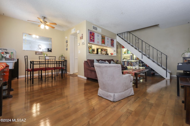 living room with a textured ceiling, hardwood / wood-style flooring, and ceiling fan