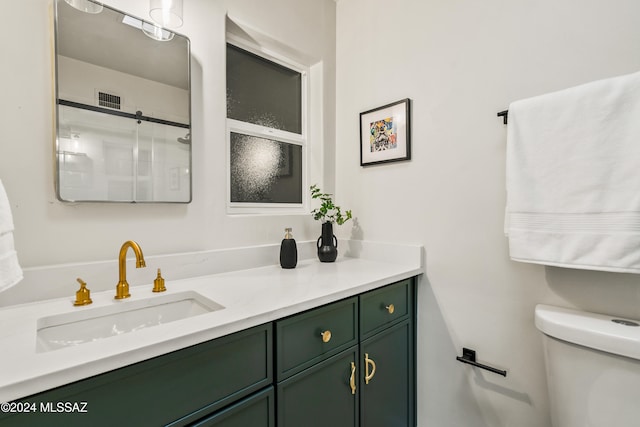 bathroom with walk in shower, vanity, and toilet