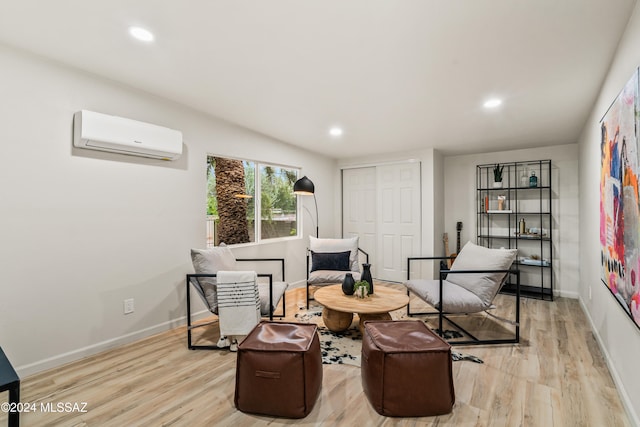 sitting room with a wall mounted AC and light hardwood / wood-style flooring