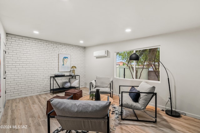 interior space featuring light hardwood / wood-style floors, brick wall, and an AC wall unit