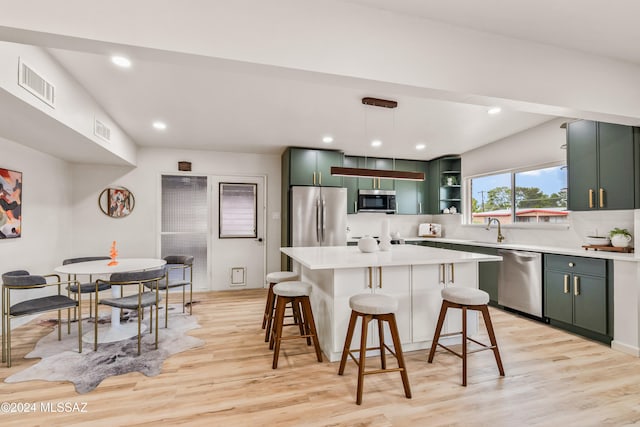 kitchen with light wood-type flooring, a kitchen island, pendant lighting, and stainless steel appliances