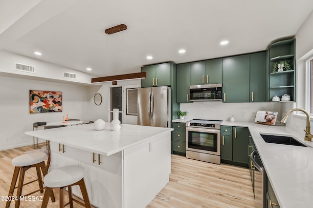 kitchen with light hardwood / wood-style floors, sink, appliances with stainless steel finishes, and green cabinetry