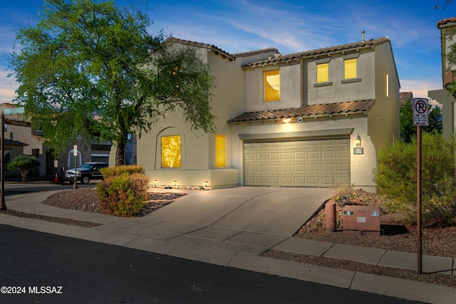 mediterranean / spanish home featuring a garage, concrete driveway, a tiled roof, and stucco siding