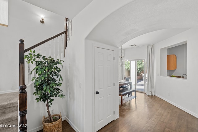 hallway featuring stairway, baseboards, arched walkways, and wood finished floors