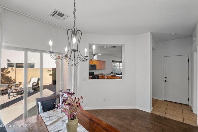 dining area with a notable chandelier, baseboards, visible vents, and wood finished floors