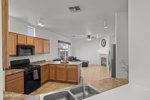 kitchen featuring light tile patterned floors, visible vents, open floor plan, black appliances, and a sink