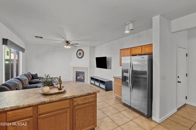 kitchen featuring visible vents, open floor plan, ceiling fan, a tile fireplace, and stainless steel fridge with ice dispenser