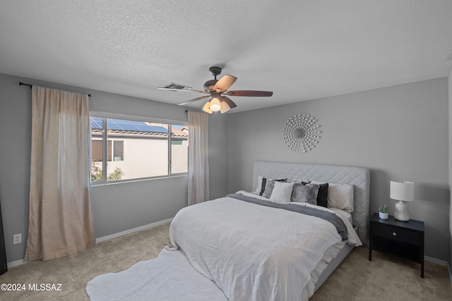 bedroom with carpet floors, visible vents, a textured ceiling, and baseboards