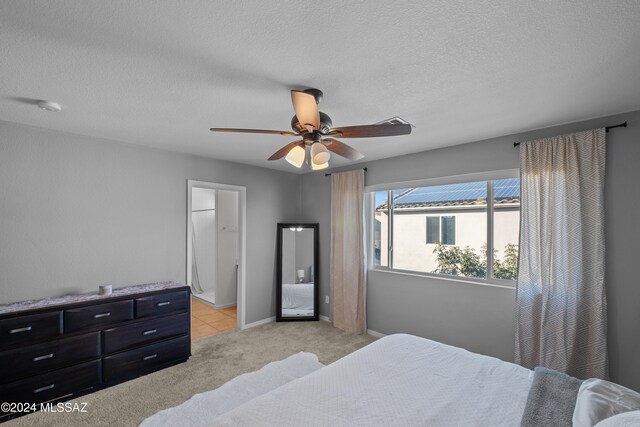 bedroom with a textured ceiling, ceiling fan, light colored carpet, and baseboards