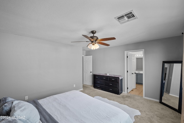 bedroom featuring baseboards, visible vents, light colored carpet, ceiling fan, and a textured ceiling