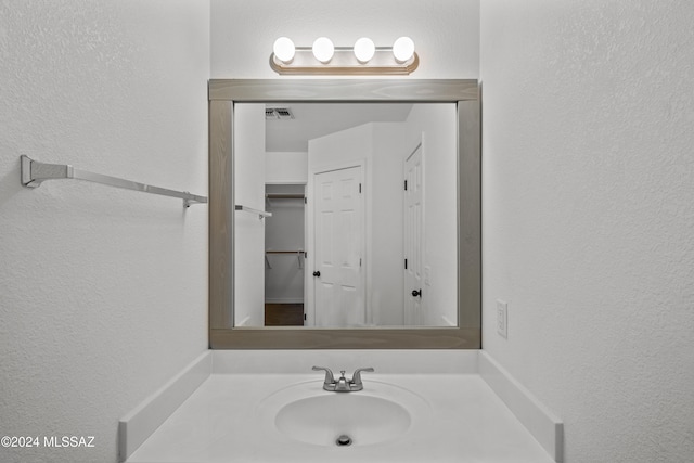 bathroom featuring visible vents, a textured wall, and vanity