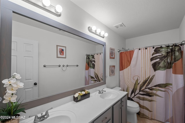 full bath with visible vents, double vanity, a sink, and toilet