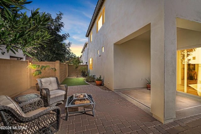 patio terrace at dusk with an outdoor fire pit and a fenced backyard