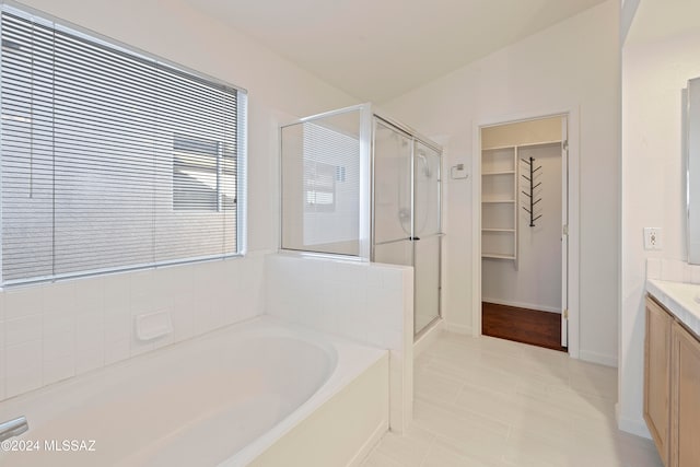 bathroom with plus walk in shower, vanity, vaulted ceiling, and tile patterned floors