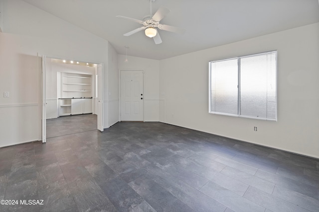 empty room featuring built in shelves, lofted ceiling, and ceiling fan