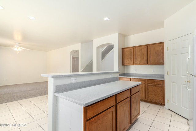 kitchen featuring light tile patterned flooring, ceiling fan, white fridge, and a center island