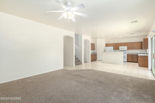 unfurnished living room with light tile patterned flooring, ceiling fan, and sink