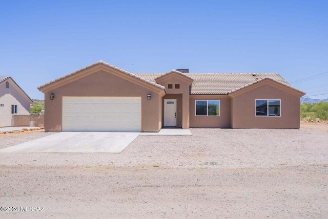 ranch-style house featuring stucco siding, a tiled roof, driveway, and a garage