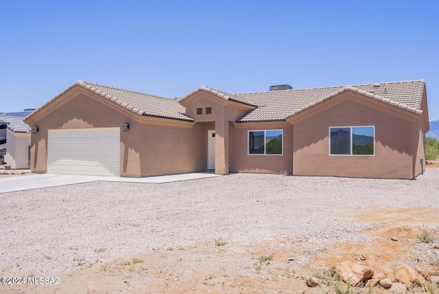view of front facade featuring an attached garage, a tile roof, concrete driveway, and stucco siding