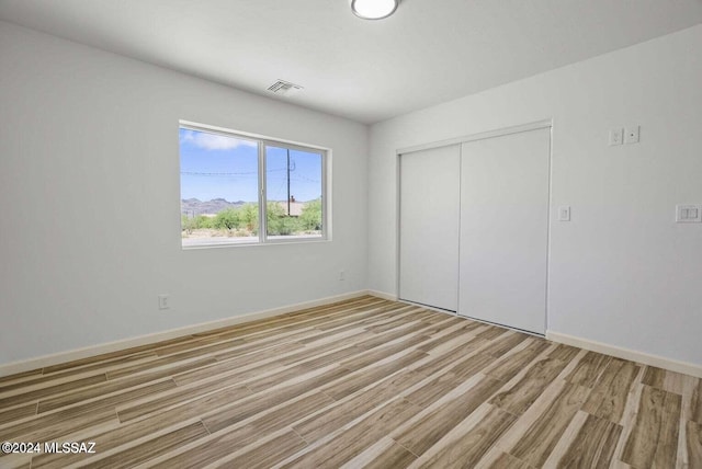 unfurnished bedroom with a closet and light wood-type flooring