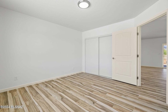 unfurnished bedroom featuring light hardwood / wood-style floors and a closet