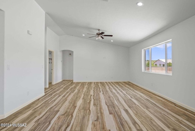 empty room with ceiling fan, lofted ceiling, and light wood-type flooring