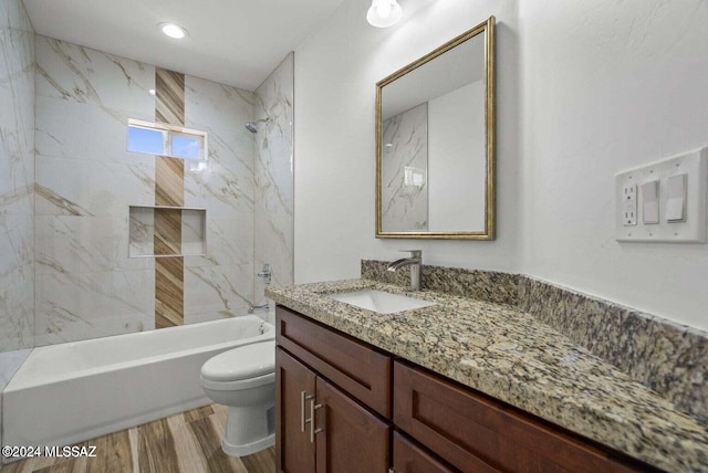 full bathroom with tiled shower / bath, vanity, toilet, and hardwood / wood-style floors