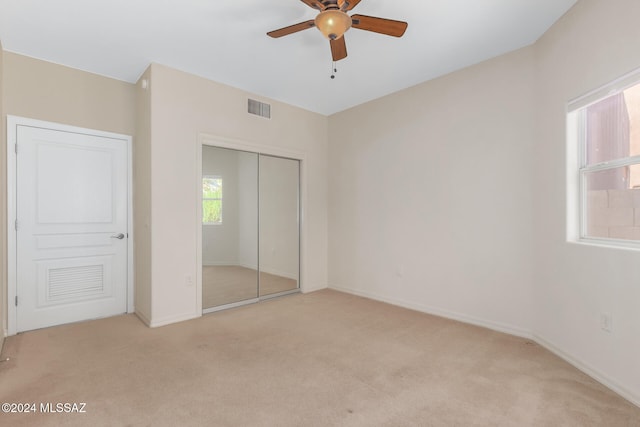 unfurnished bedroom with light carpet, ceiling fan, and a closet