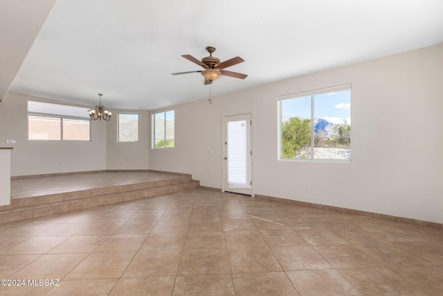 empty room featuring ceiling fan with notable chandelier and light tile patterned floors