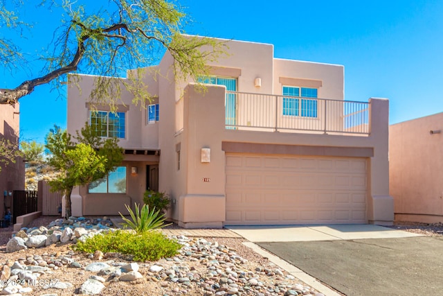 pueblo-style house with a garage and a balcony