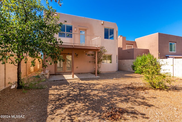 back of property with a balcony, french doors, and a patio area