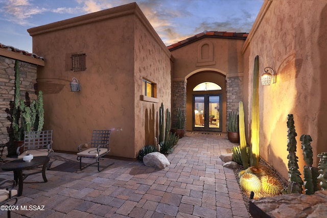 exterior entry at dusk with a patio area and french doors