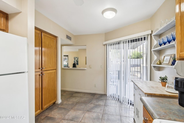 kitchen with dark tile patterned flooring and white refrigerator