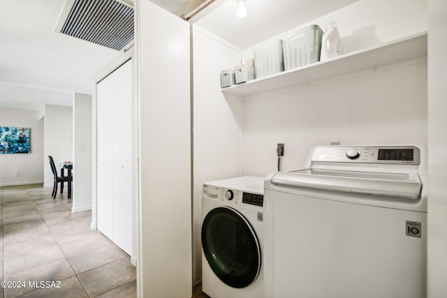 laundry area with washing machine and dryer and light tile patterned floors