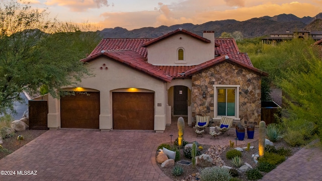 mediterranean / spanish-style house featuring a mountain view, a garage, and a patio area