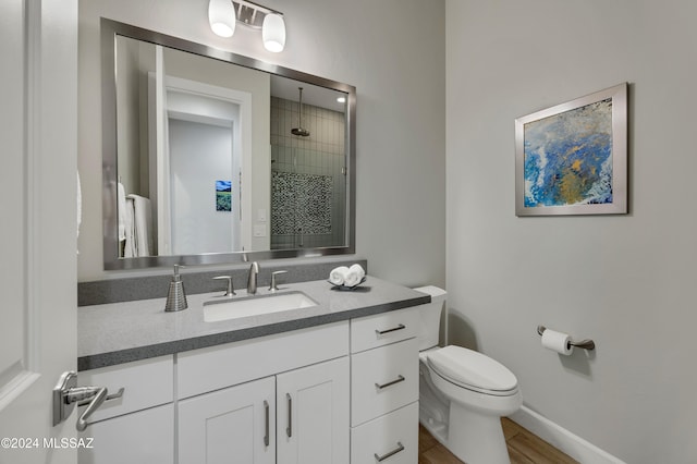 bathroom with vanity, toilet, wood-type flooring, and a tile shower