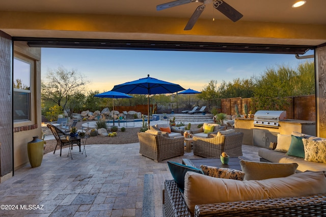 patio terrace at dusk featuring ceiling fan, a grill, an outdoor hangout area, and area for grilling