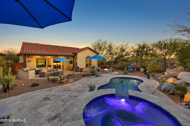 pool at dusk with an outdoor living space, a patio area, and an in ground hot tub