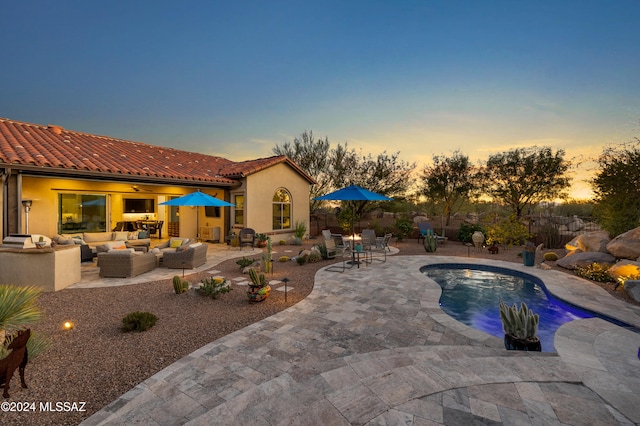 pool at dusk with outdoor lounge area and a patio