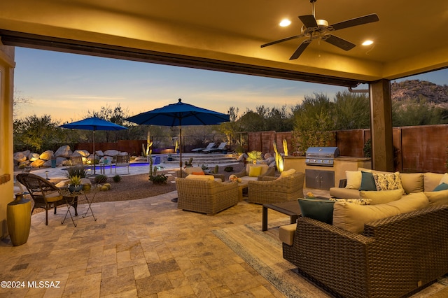 patio terrace at dusk with ceiling fan, area for grilling, and an outdoor hangout area