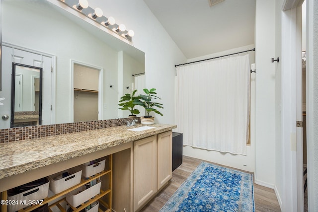 bathroom with shower / bathtub combination with curtain, wood-type flooring, vanity, and vaulted ceiling