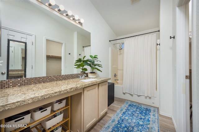 bathroom featuring hardwood / wood-style floors, vanity, vaulted ceiling, and shower / tub combo