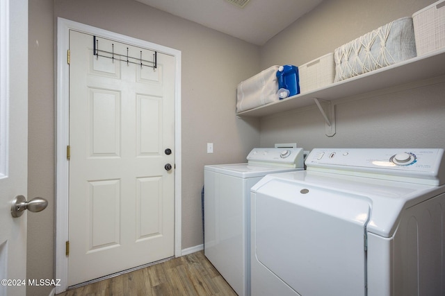 washroom with washing machine and clothes dryer and light hardwood / wood-style floors