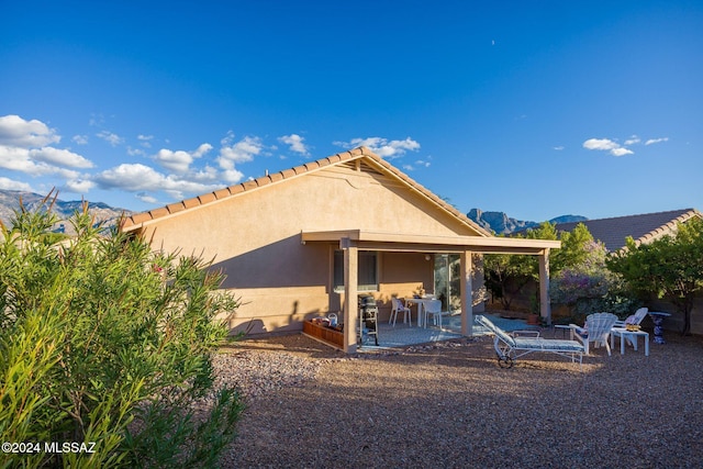 back of property featuring a mountain view and a patio area