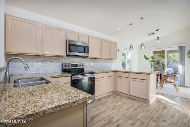 kitchen featuring appliances with stainless steel finishes, sink, vaulted ceiling, kitchen peninsula, and light hardwood / wood-style flooring