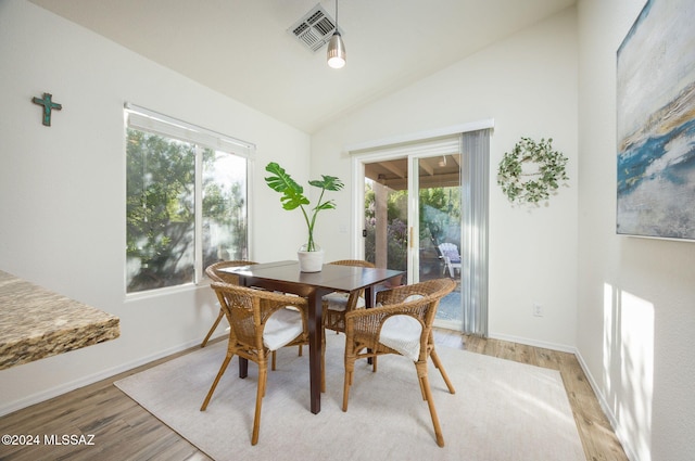 dining space with lofted ceiling, a healthy amount of sunlight, and light hardwood / wood-style flooring