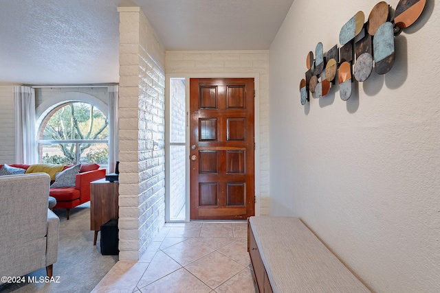 foyer entrance featuring a textured ceiling, a textured wall, and light tile patterned flooring